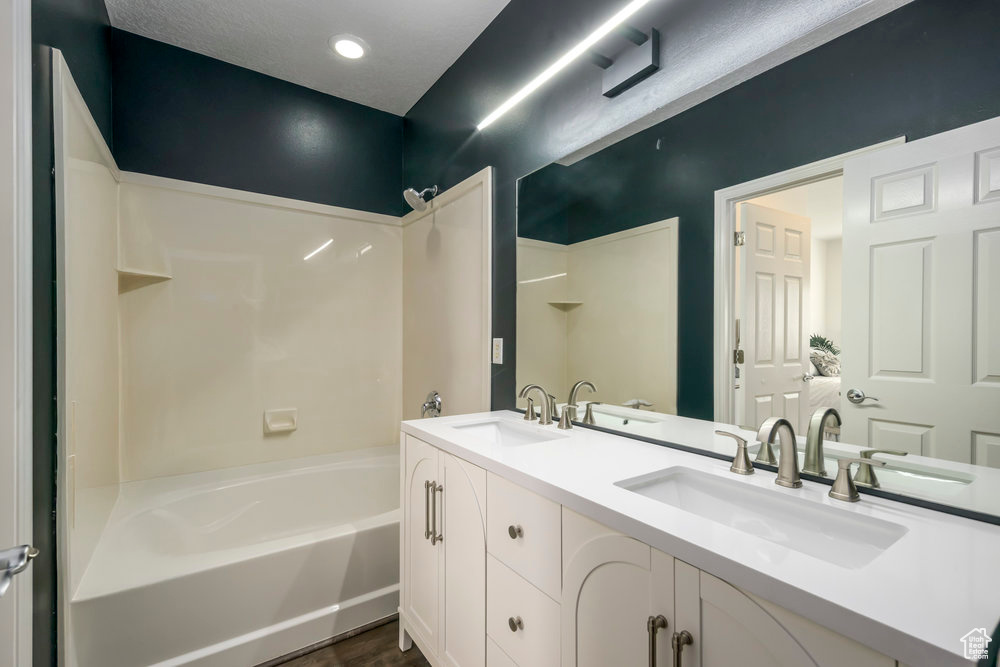 Full bathroom with double vanity, shower / tub combination, and a sink