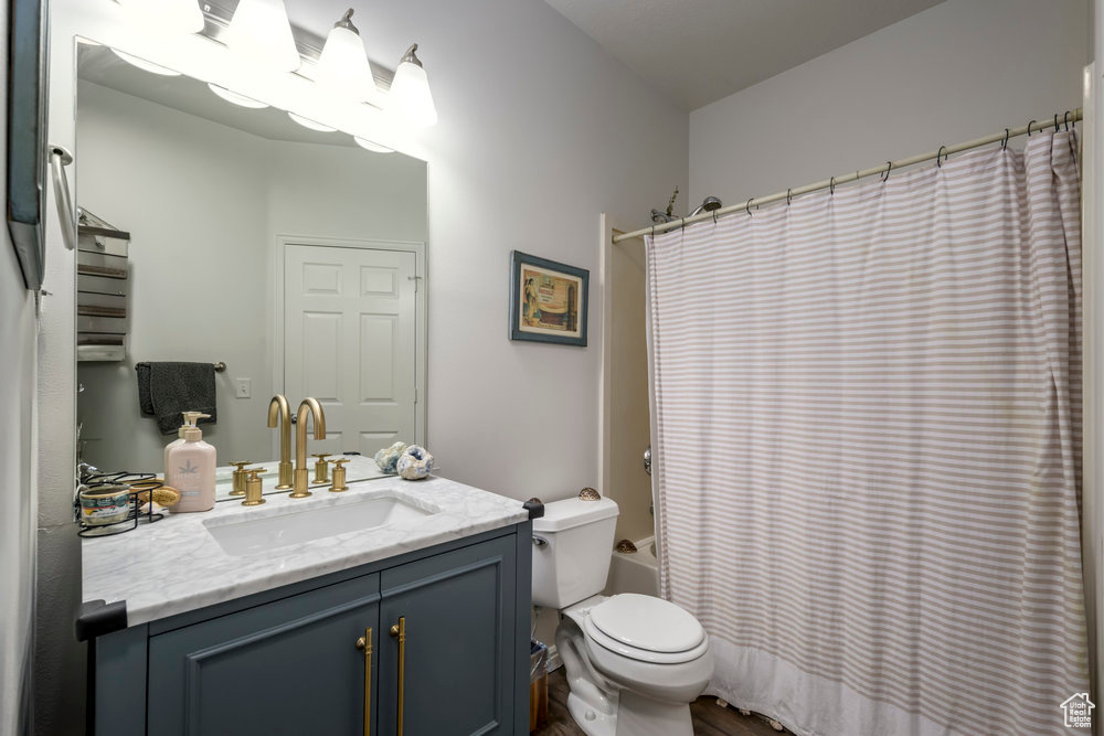 Bathroom with toilet, shower / bath combination with curtain, and vanity