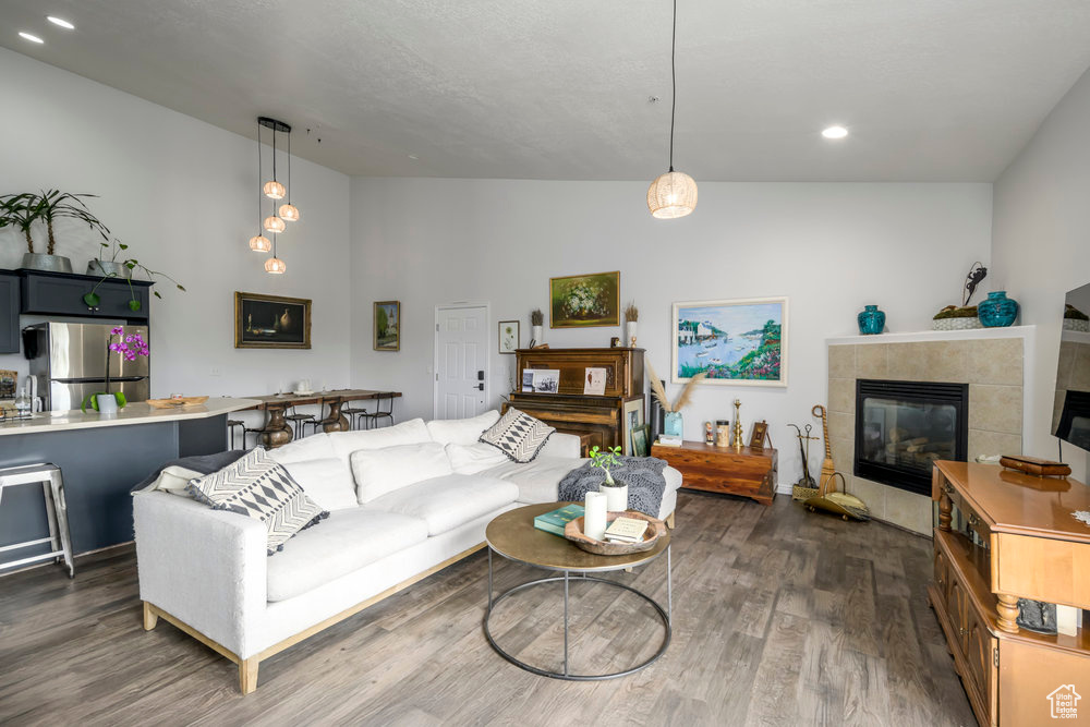 Living room featuring a tiled fireplace, recessed lighting, and dark wood-type flooring