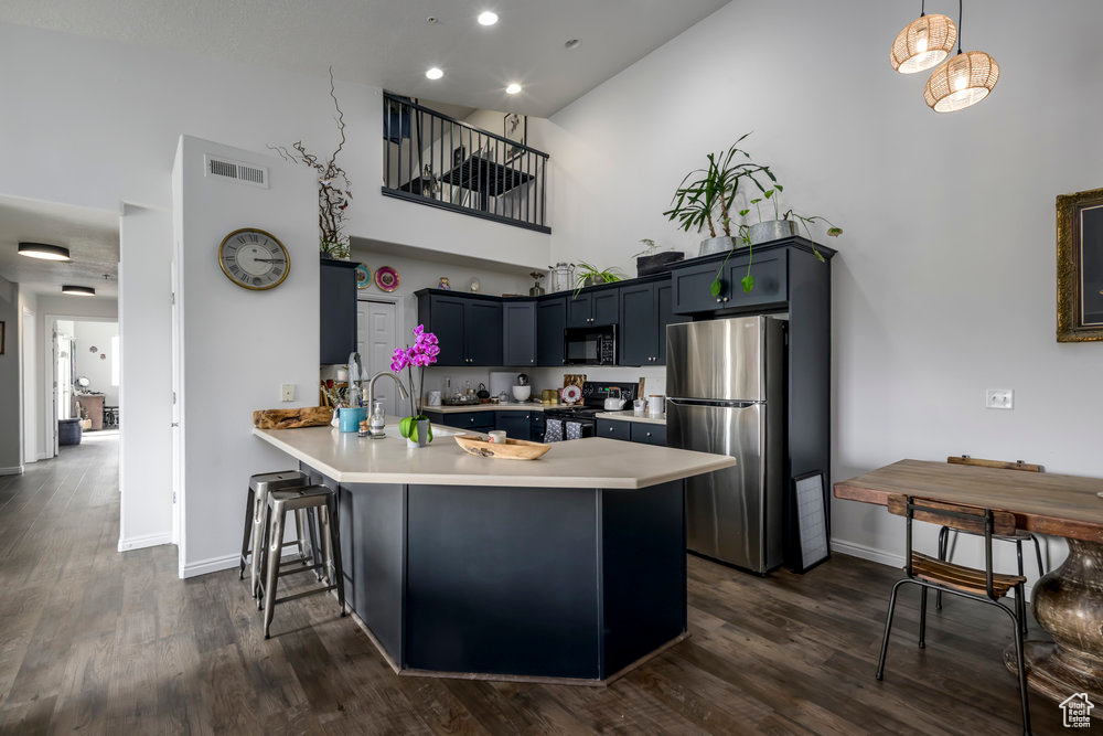 Kitchen featuring visible vents, freestanding refrigerator, a peninsula, black microwave, and range with electric cooktop