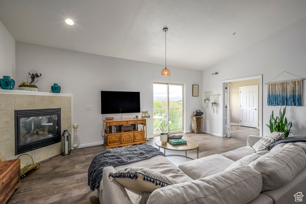 Living room with baseboards, visible vents, wood finished floors, and lofted ceiling