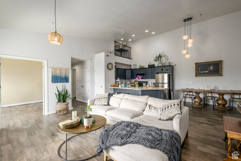 Living area with high vaulted ceiling, baseboards, recessed lighting, and wood finished floors