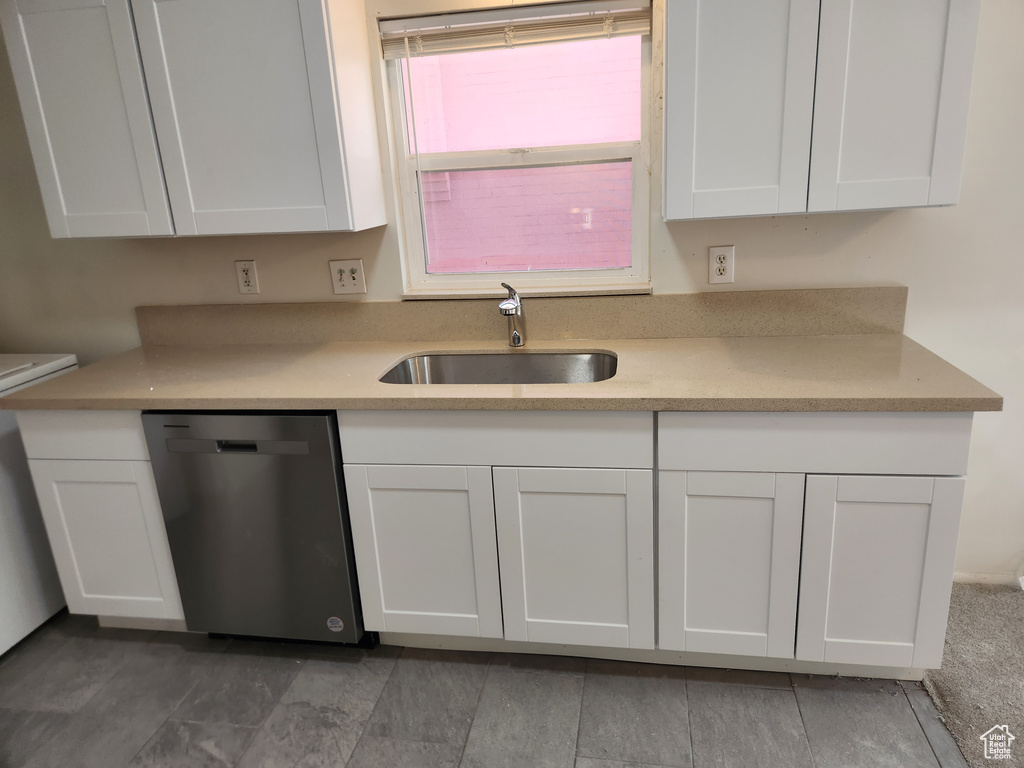 Kitchen with dishwasher, a sink, and white cabinetry