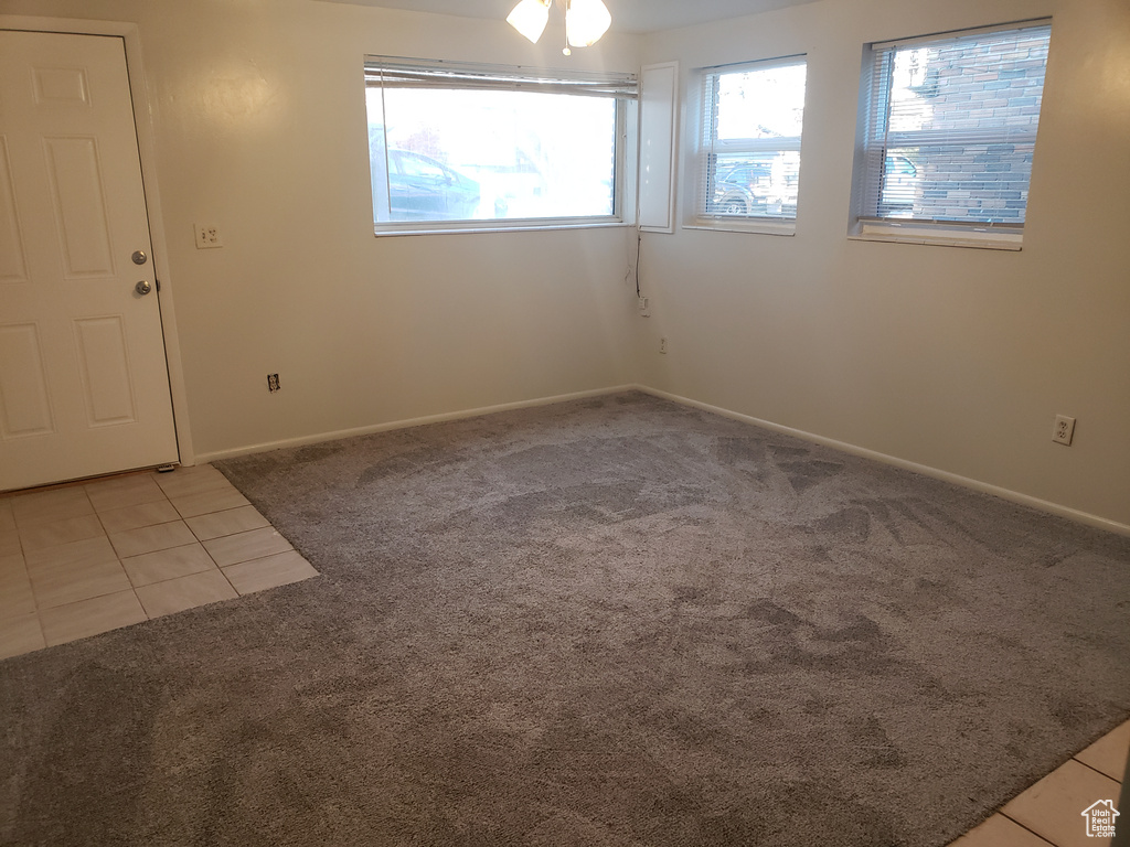Spare room with light tile patterned flooring, ceiling fan, baseboards, and light carpet