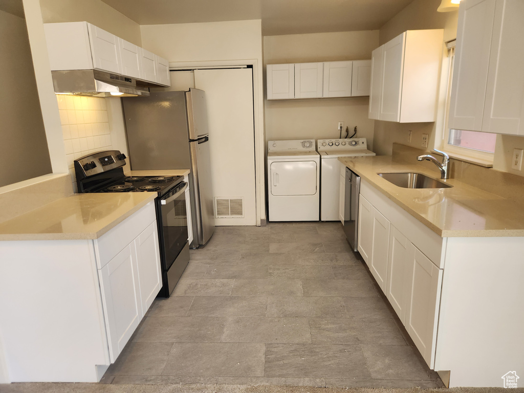 Kitchen with visible vents, stainless steel appliances, under cabinet range hood, a sink, and washing machine and dryer