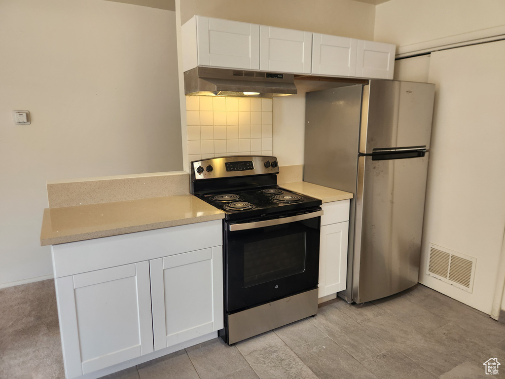 Kitchen featuring white cabinetry, appliances with stainless steel finishes, under cabinet range hood, visible vents, and decorative backsplash