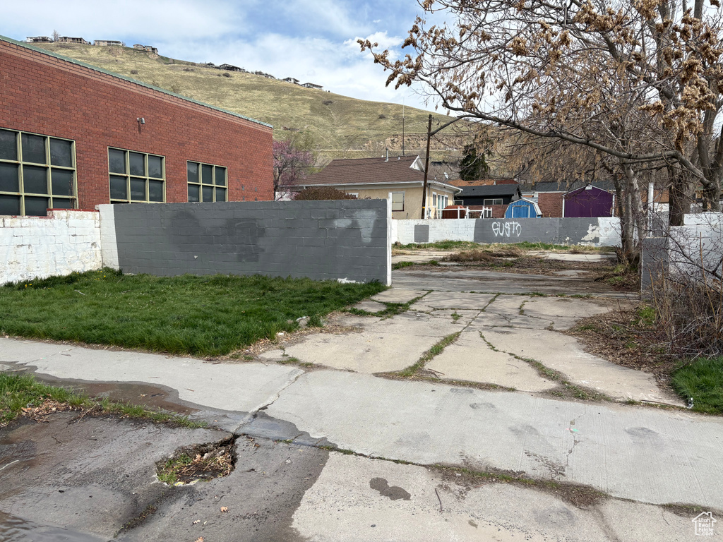 View of side of home with fence, a mountain view, and brick siding
