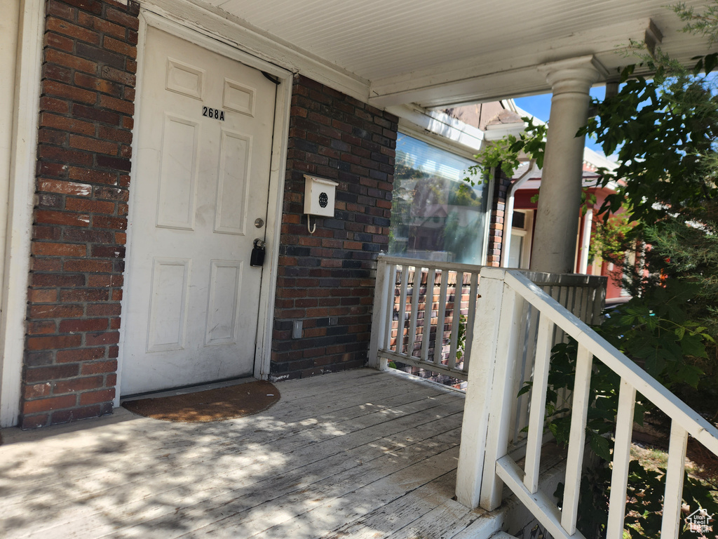 View of exterior entry featuring brick siding and a porch