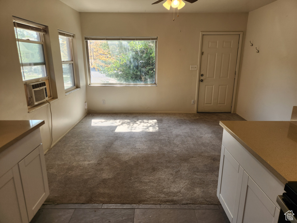 Unfurnished dining area with cooling unit, a ceiling fan, dark tile patterned floors, and dark carpet