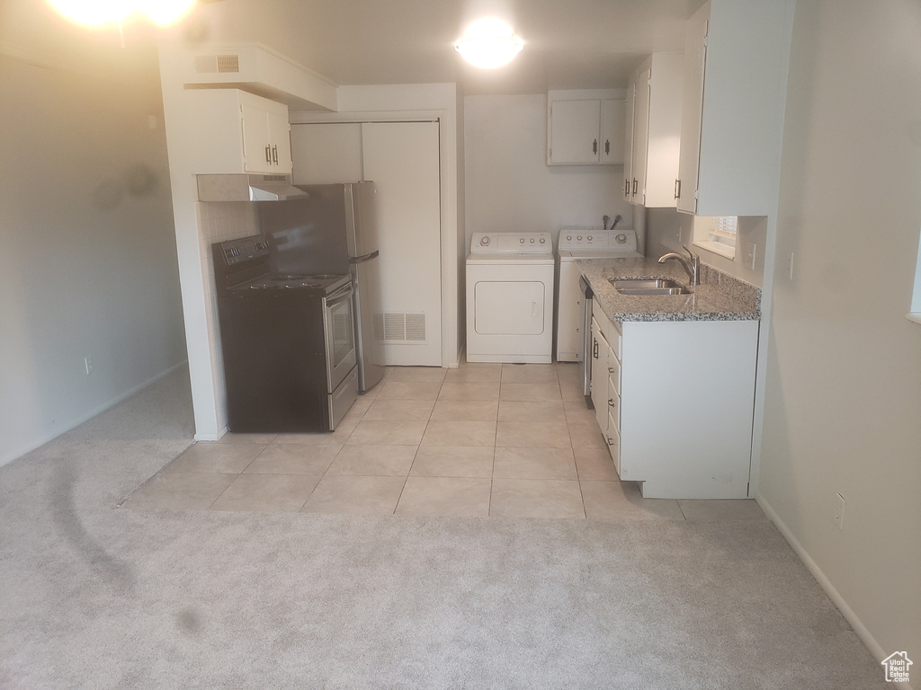Kitchen featuring washing machine and clothes dryer, visible vents, white cabinets, and a sink