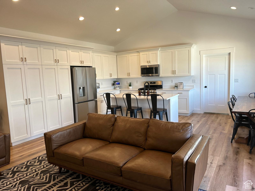 Living area featuring recessed lighting, high vaulted ceiling, and light wood-type flooring