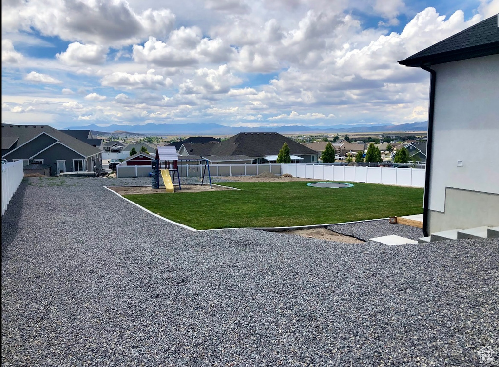 View of yard featuring a playground, fence, and a residential view