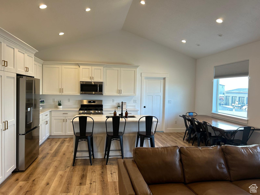Kitchen featuring light countertops, white cabinetry, open floor plan, and appliances with stainless steel finishes