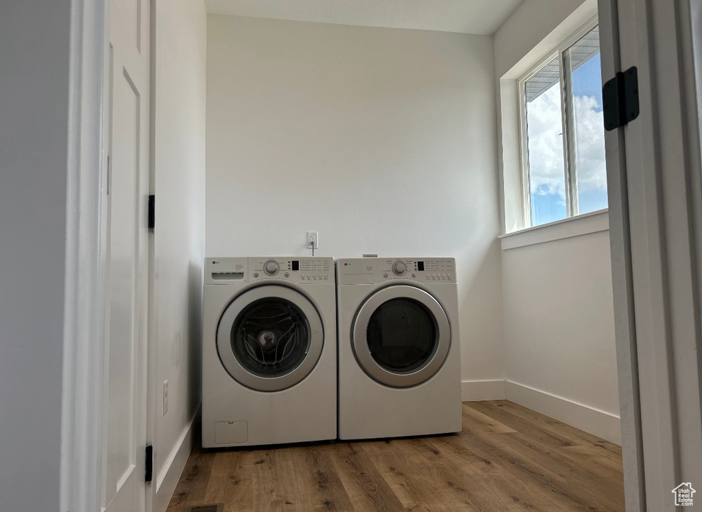 Laundry room featuring laundry area, baseboards, wood finished floors, and washing machine and clothes dryer