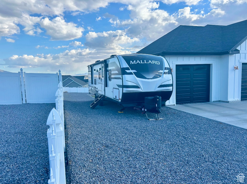 Exterior space with concrete driveway, fence, and a garage