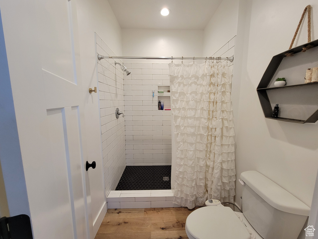 Bathroom featuring recessed lighting, tiled shower, toilet, and wood finished floors