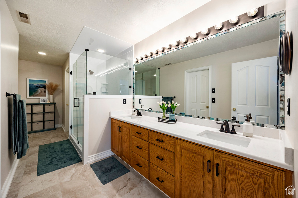 Bathroom featuring double vanity, a shower stall, and baseboards