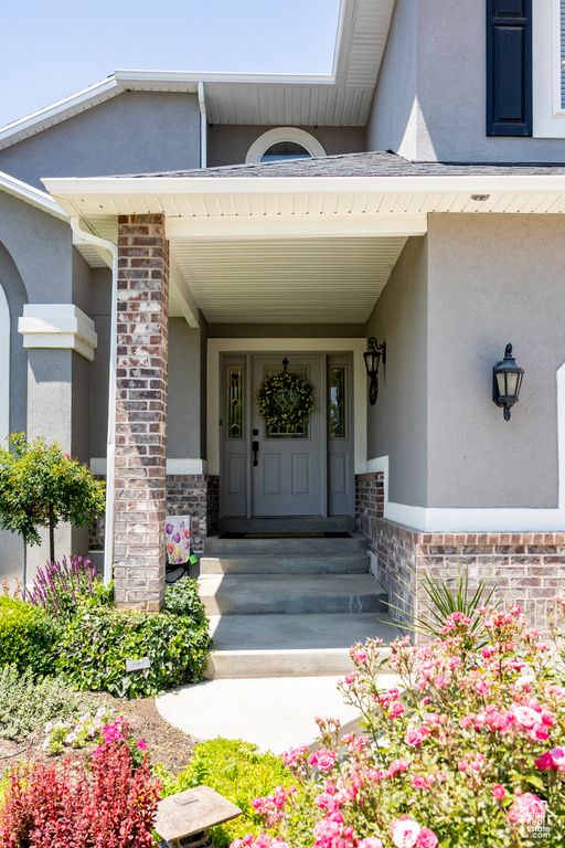 Doorway to property featuring stucco siding, a porch, and brick siding