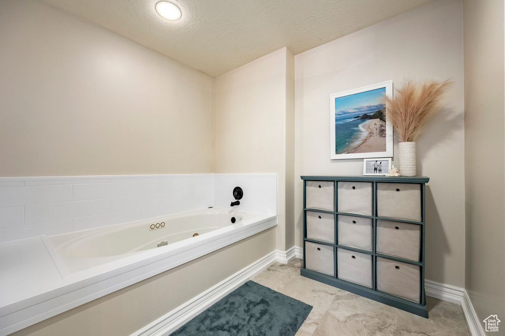 Bathroom featuring a jetted tub, baseboards, a textured ceiling, and vanity