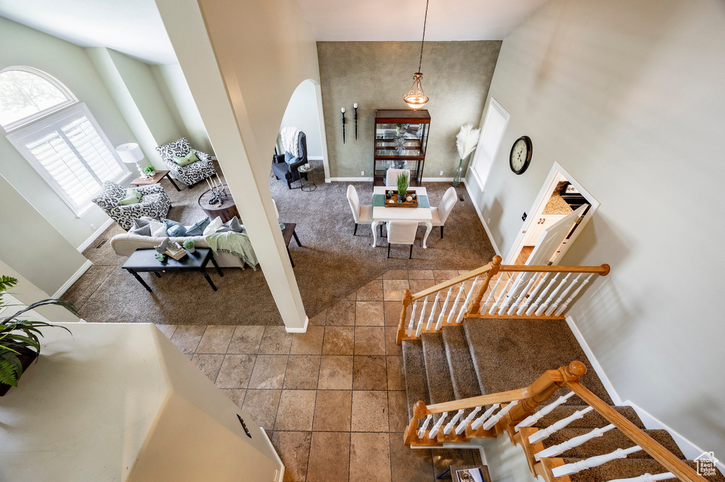 Living area with arched walkways, a high ceiling, baseboards, stairway, and carpet flooring