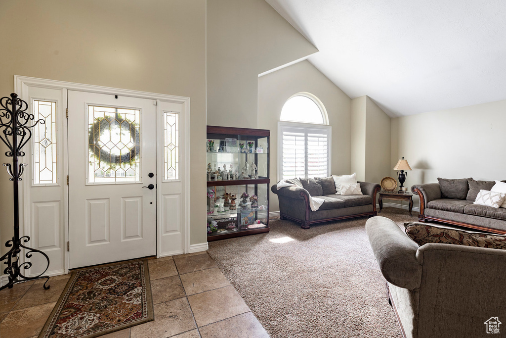Entryway with high vaulted ceiling, baseboards, and carpet
