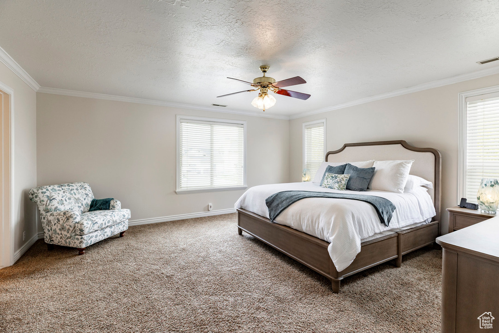 Bedroom featuring crown molding, carpet flooring, a textured ceiling, a ceiling fan, and visible vents