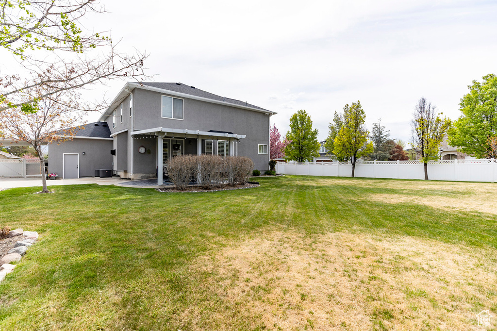 Back of house featuring a patio area, stucco siding, a yard, and fence