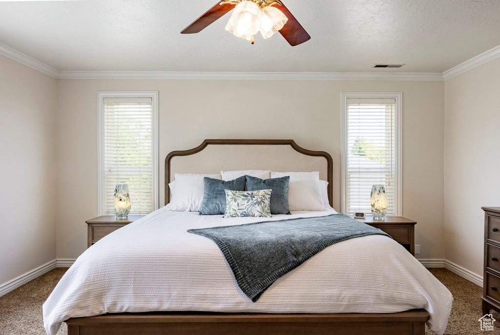 Carpeted bedroom featuring baseboards, crown molding, and a ceiling fan