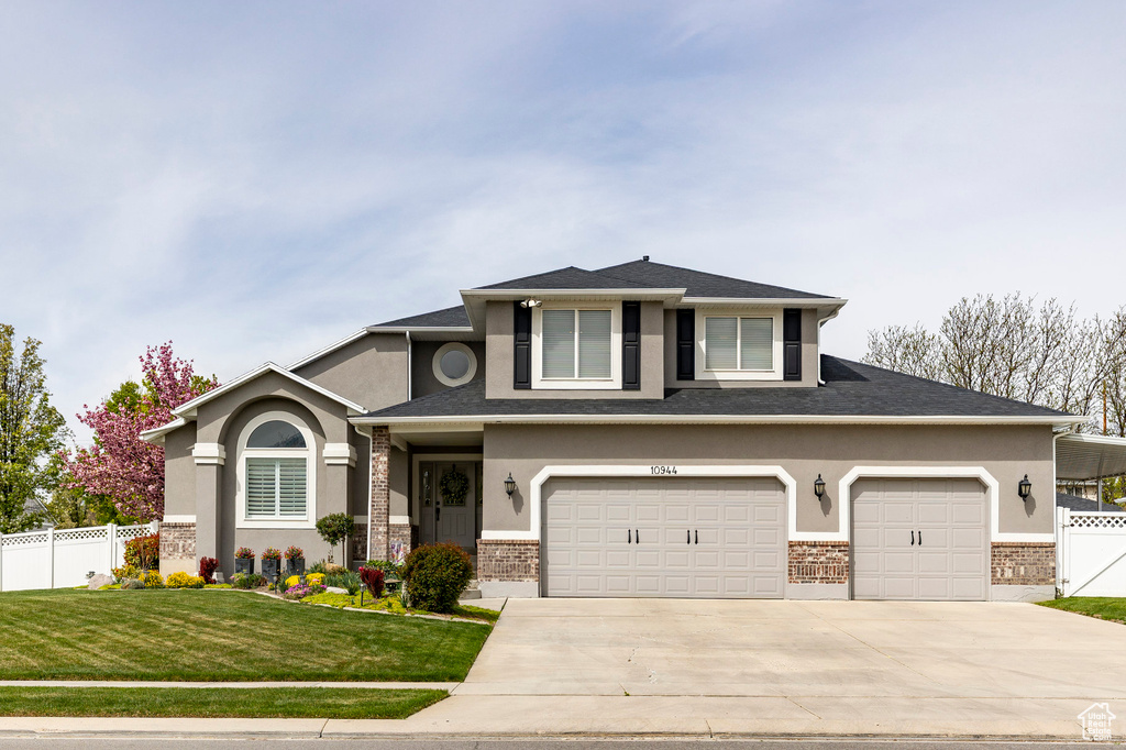 View of front of property featuring brick siding, a front lawn, fence, and driveway