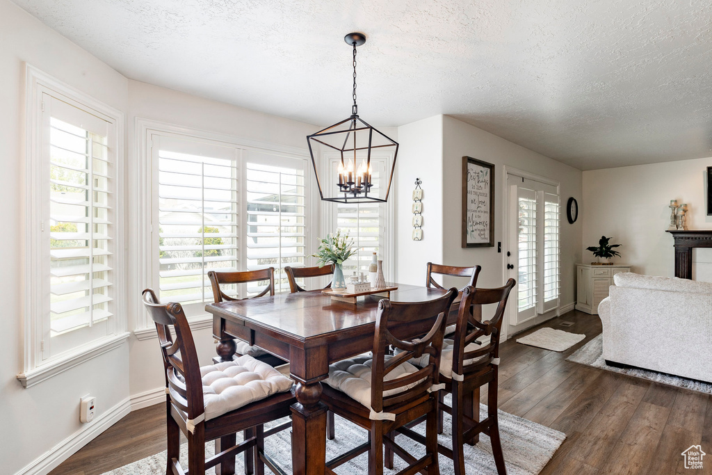 Dining space featuring baseboards, dark wood finished floors, a textured ceiling, and a notable chandelier