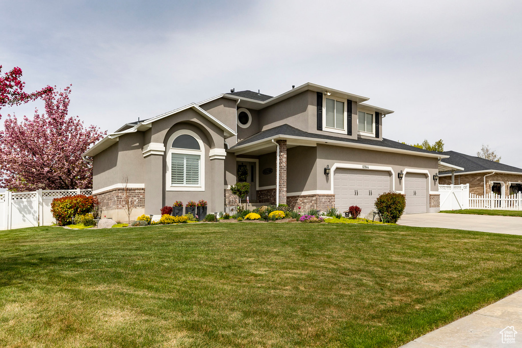View of front of home featuring stucco siding, a garage, fence, and driveway