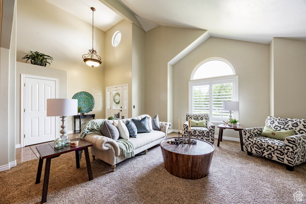 Living area featuring carpet flooring, high vaulted ceiling, and baseboards