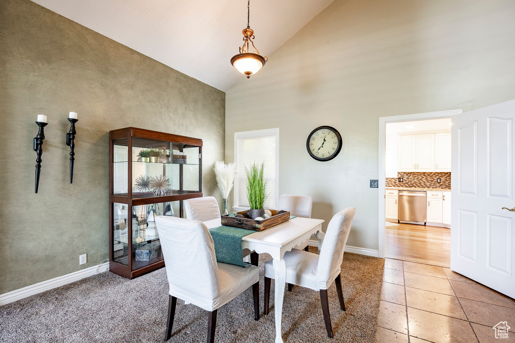 Dining room with high vaulted ceiling, light tile patterned floors, and baseboards