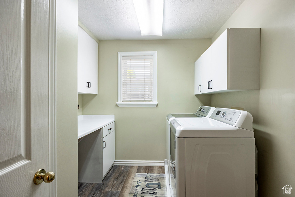 Washroom with washer and dryer, cabinet space, dark wood finished floors, a textured ceiling, and baseboards