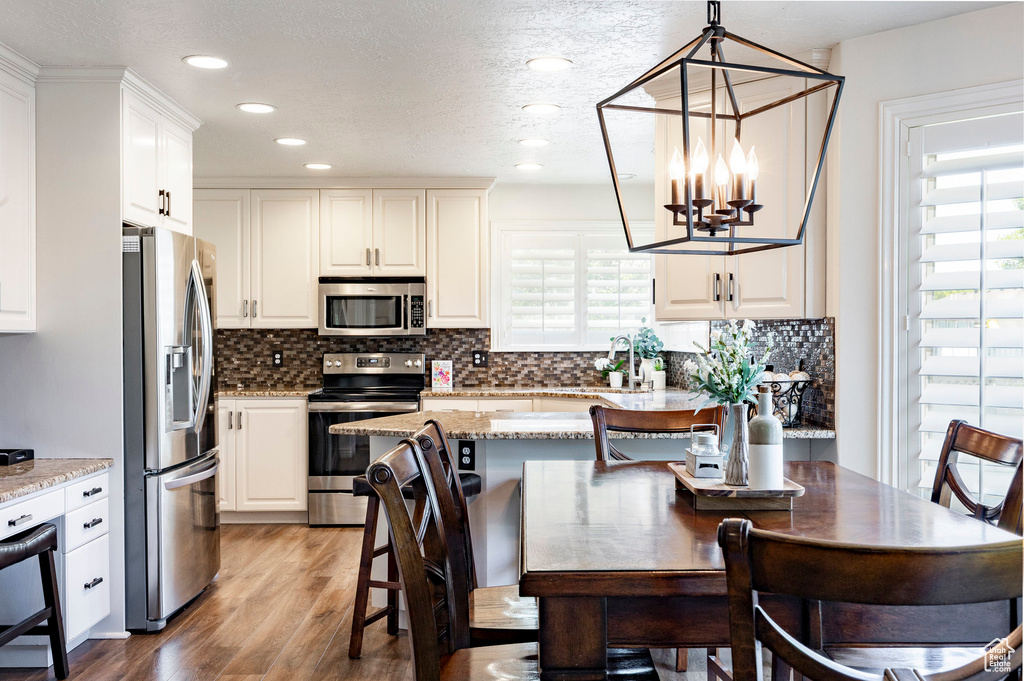 Kitchen with appliances with stainless steel finishes, plenty of natural light, a chandelier, light wood finished floors, and recessed lighting
