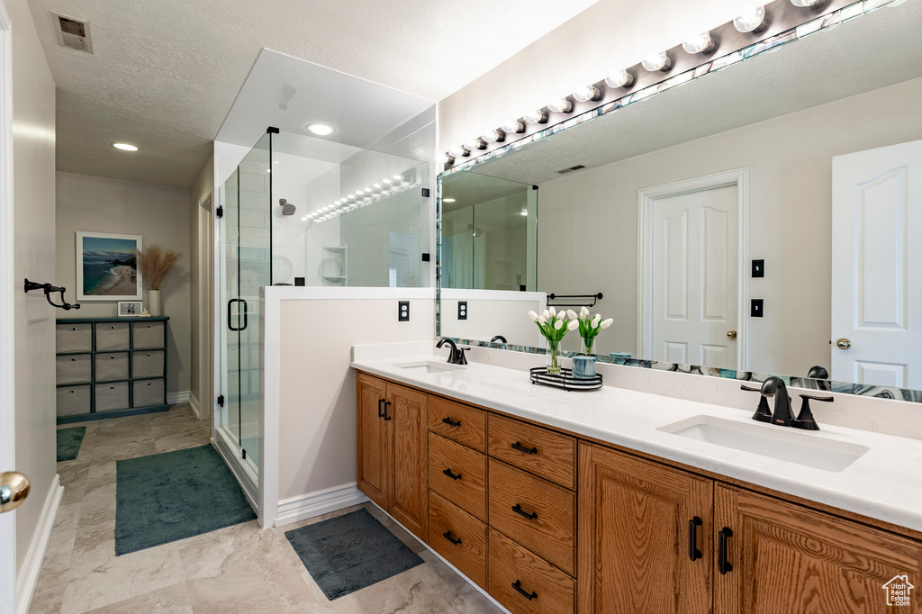 Full bath with double vanity, baseboards, a shower stall, and a sink