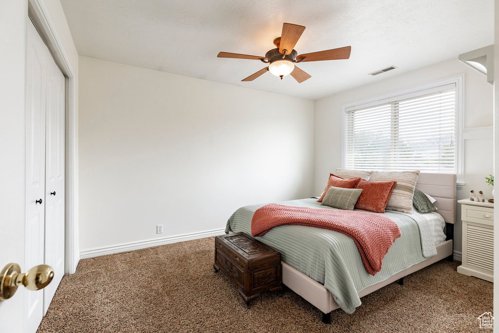 Carpeted bedroom with a closet, a ceiling fan, baseboards, and visible vents