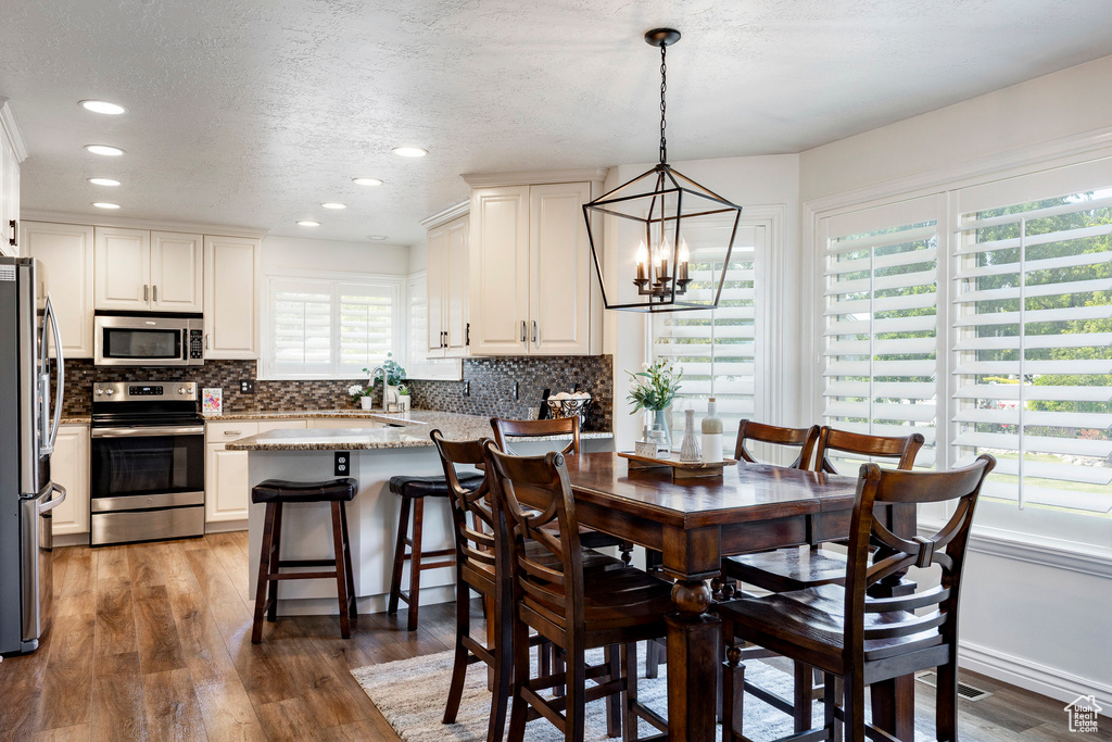Dining room with a chandelier, wood finished floors, recessed lighting, and a textured ceiling