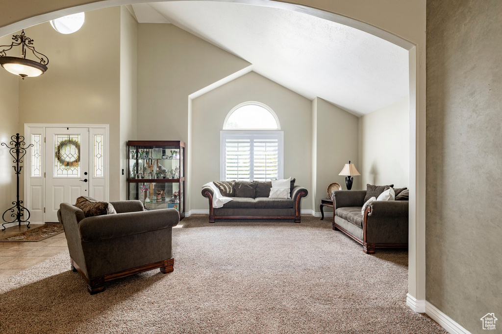 Carpeted living room featuring baseboards, arched walkways, and high vaulted ceiling