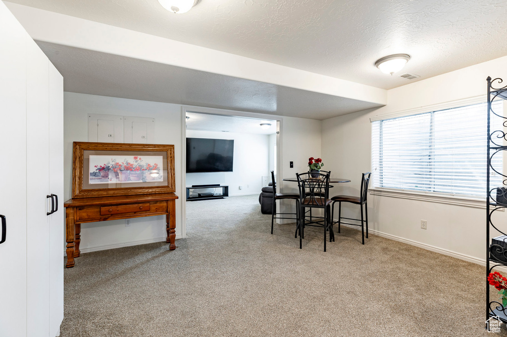 Carpeted dining area with baseboards, a textured ceiling, and visible vents