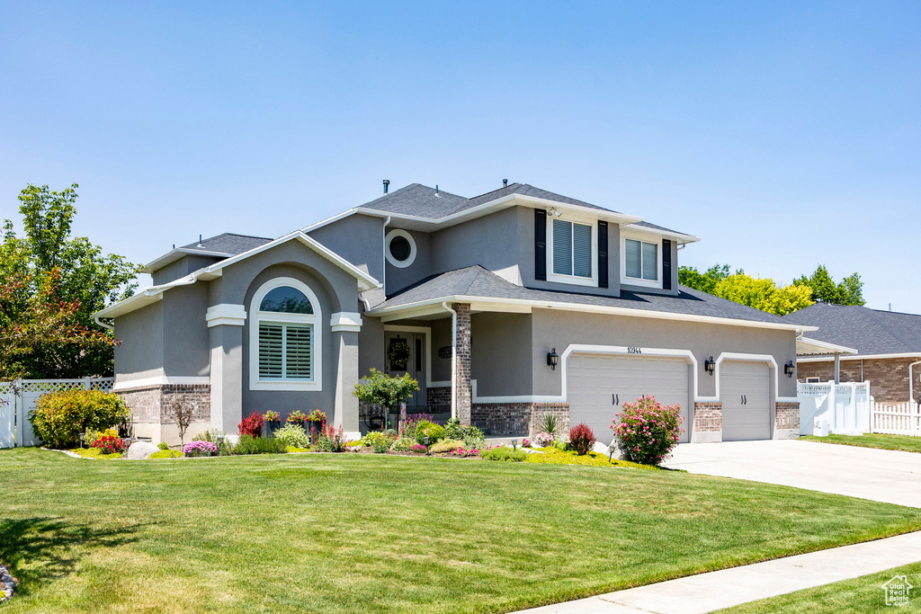 Prairie-style home with stucco siding, driveway, stone siding, and an attached garage