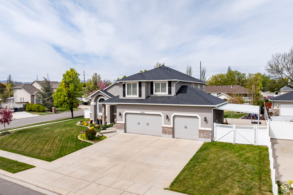 View of front of house featuring a front yard, fence, concrete driveway, a shingled roof, and stucco siding