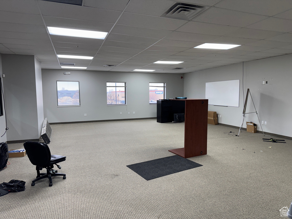 Carpeted office space featuring baseboards, a drop ceiling, and visible vents