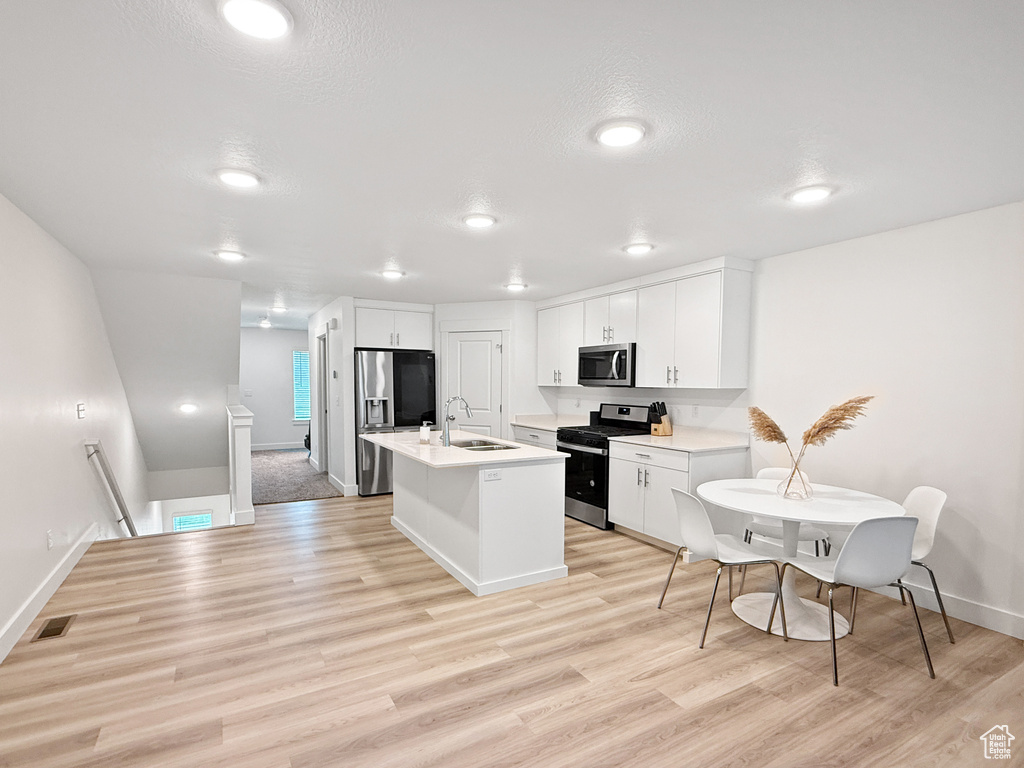 Kitchen featuring light countertops, stainless steel appliances, a sink, and light wood-type flooring