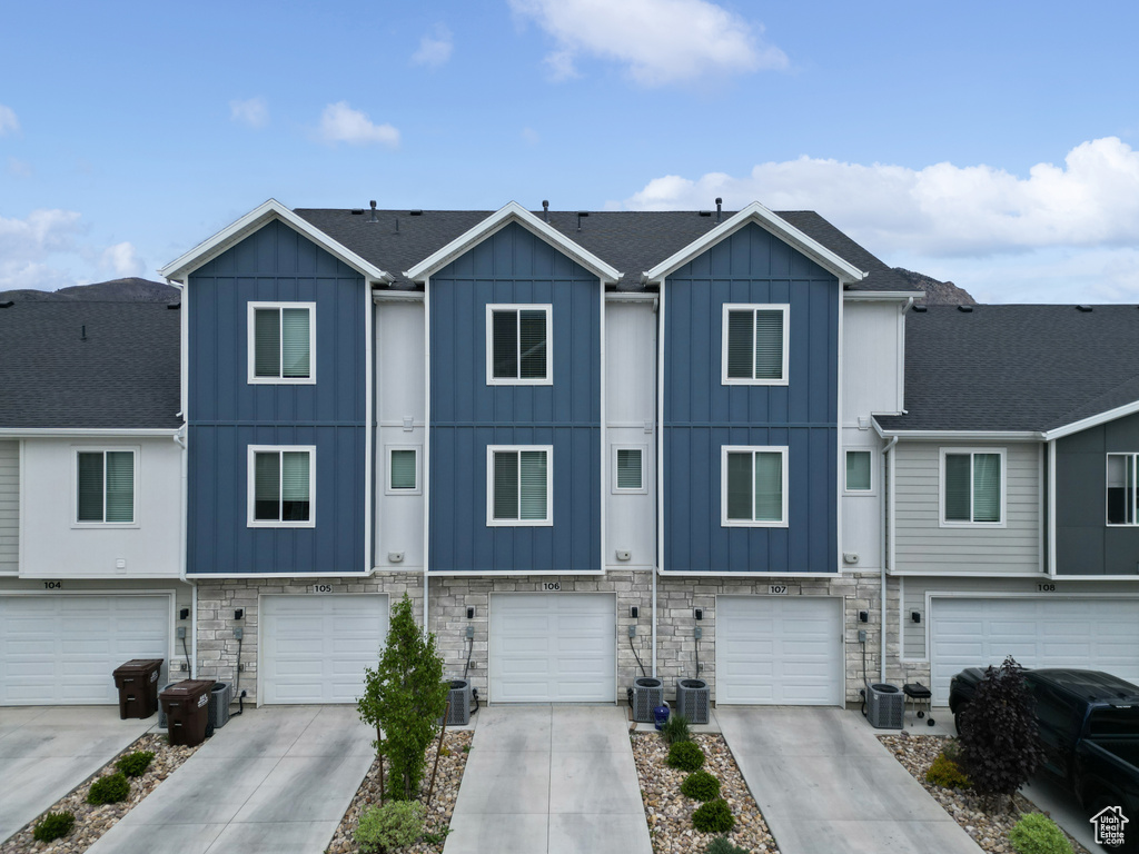 View of property with a garage, board and batten siding, driveway, and stone siding