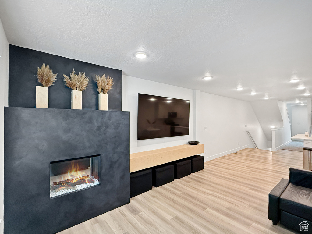 Living room featuring baseboards, a glass covered fireplace, and light wood-type flooring