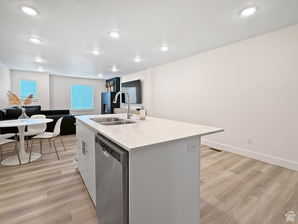 Kitchen with a sink, light wood finished floors, dishwasher, recessed lighting, and a center island with sink
