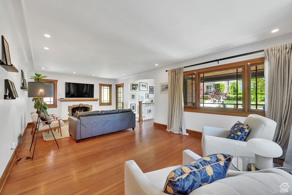 Living room featuring light wood-style floors, recessed lighting, baseboards, and a lit fireplace