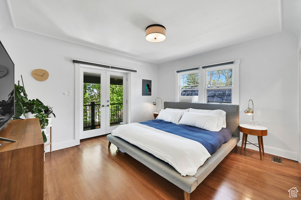 Bedroom featuring baseboards, access to outside, french doors, and wood finished floors