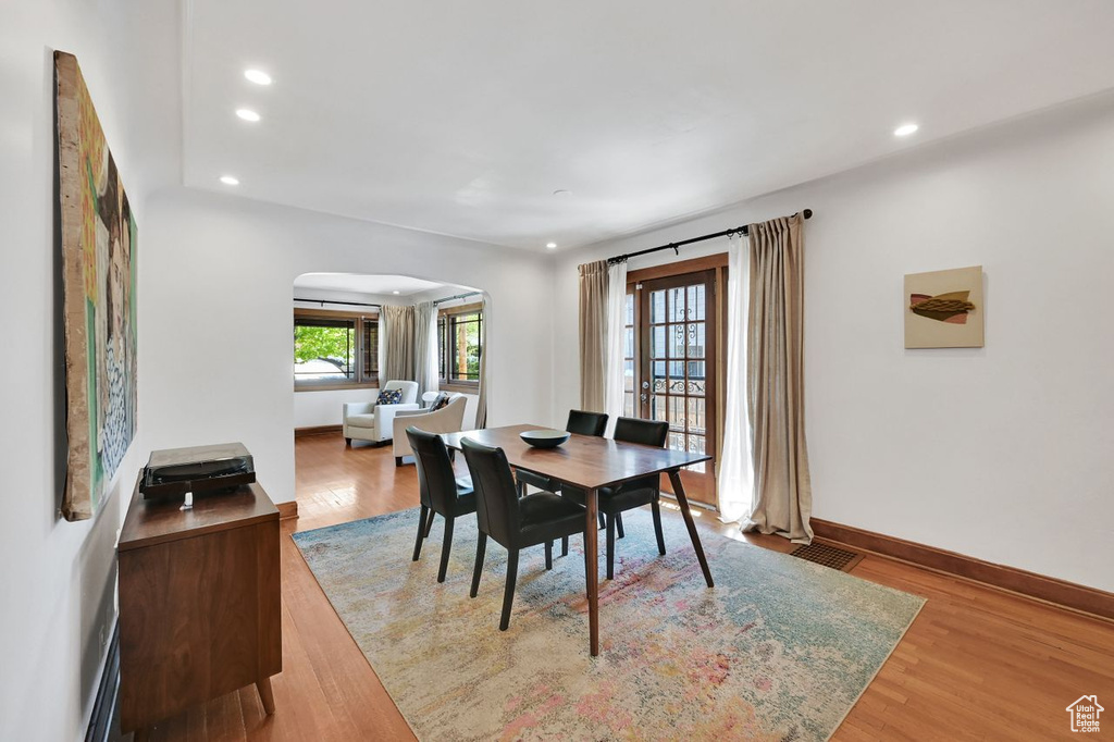 Dining room featuring arched walkways, baseboards, recessed lighting, and wood finished floors